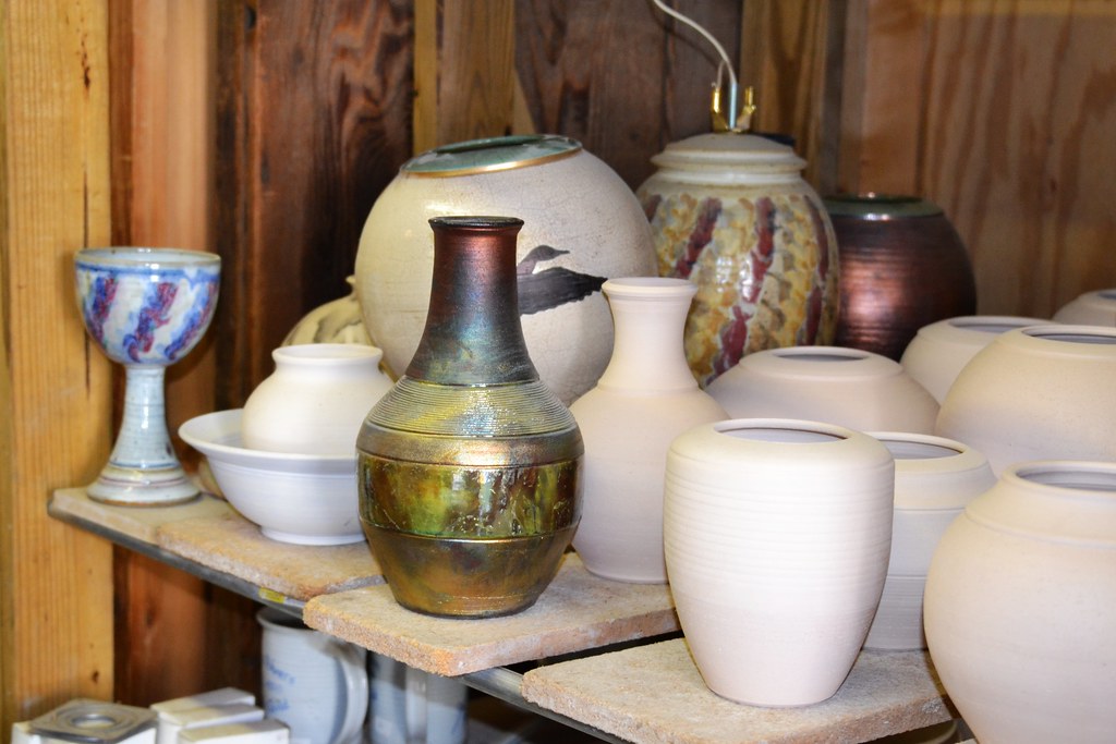 An assortment of unglazed and finished ceramic vessels on a studio shelf.